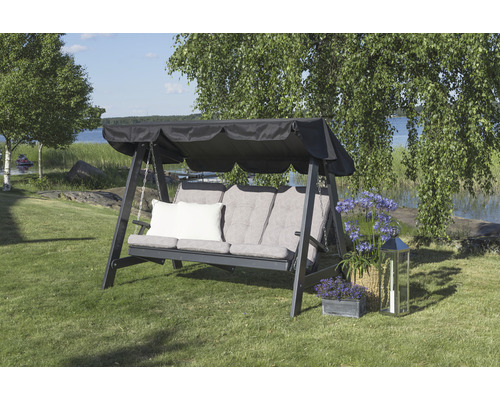 Trädgårdsgunga med dynor och solskyddstak på en gräsmatta