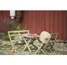 Trädgårdsmöbelset med fällbord, fällstolar och bänk framför en röd trävägg
