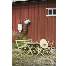 Trädgårdsscen med träbord, stolar och en stråhatt mot en röd trävägg