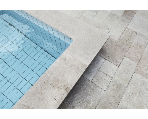 Detaljvy av en pool med travertinkant och travertinplattor