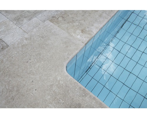 Detaljvy av en pool med travertinkant