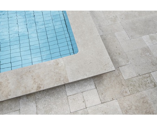 Detaljvy av en pool med travertinkant och plattor