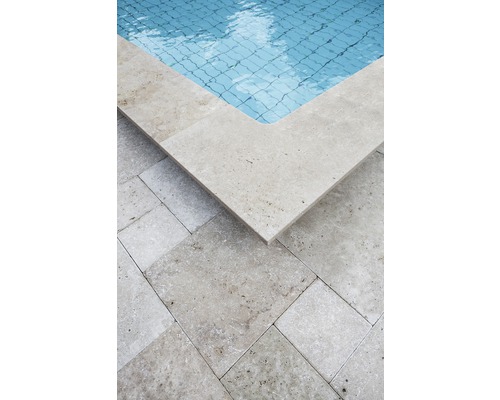 Detaljvy av en pool med travertinpoolkant och golvplattor.