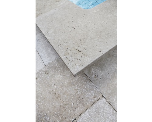 Närbild av travertinplattor runt en pool