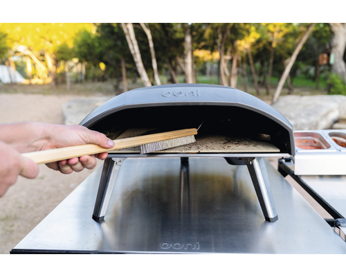 Ooni logotyp. Rengöring av en pizzaborste i en pizzaugn.