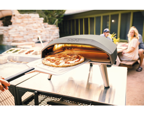 Ooni pizzaugn med pizza på pizzaspade utomhus