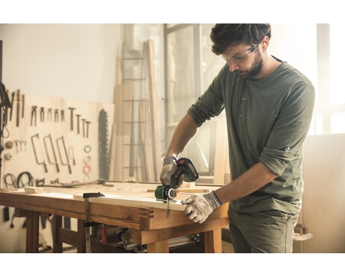 Hantverkare sågar trä med en sladdlös tigersåg i en verkstad.