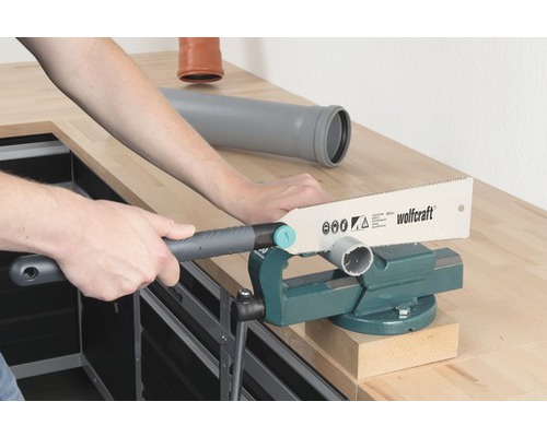 En person sågar ett rör med en metallsåg i ett skruvstäd