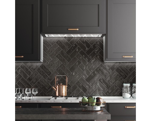 Köksscen med mörka skåp, fiskbensmönstrade plattor och köksredskap