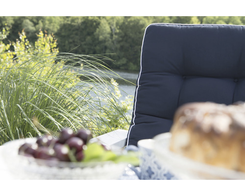 Scen med trädgårdsstolsdyna, körsbär och kaka utomhus