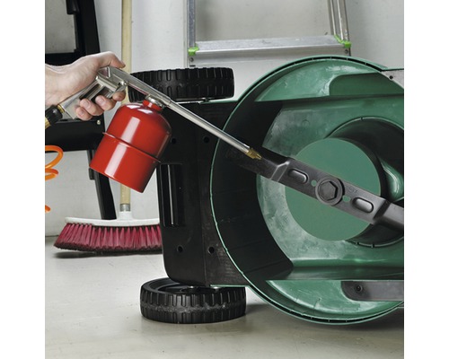 En person rengör en gräsklipparkniv med en rengöringspistol