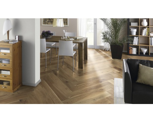 Inredningsscen med fiskbensparkett, matbord och sittplatser, bokhylla och krukväxt