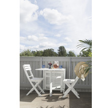 Trädgårdsscen med litet vitt fällbord och två fällstolar på en terrass med drycker.