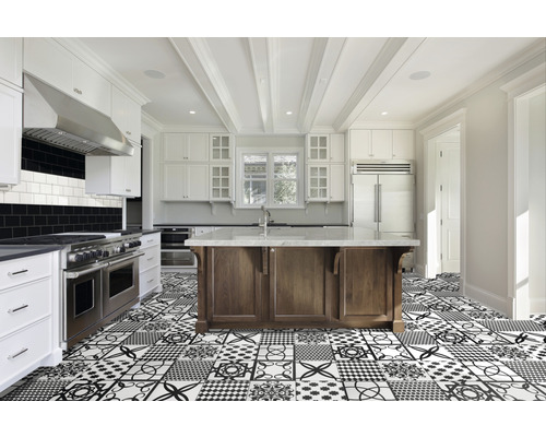 Ljust kök med köksö, vita skåp och mönstrade golvplattor