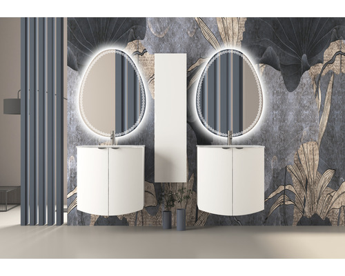 Badrum med två tvättställsskåp, belysta speglar och ett högskåp framför en blommig tapet.