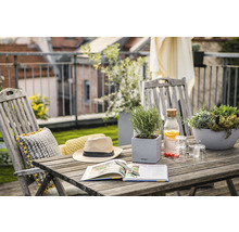 Balkongscen med träbord, stolar, växter, bok, hatt och drycker för en avkopplande atmosfär