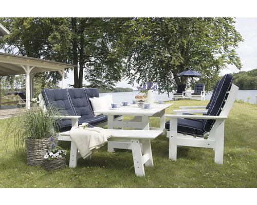 Trädgårdsscen med vita trädgårdsmöbler bestående av bänk, stol och bord på en gräsmatta