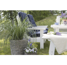 Trädgårdsmöbler med vita trästolar och bord på en gräsmatta, kompletterat med planteringskärl med gräs och blommor.