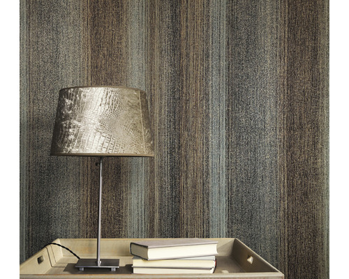 Närbild av en vägg med en tapet med randigt mönster, ett bord med en lampa och böcker