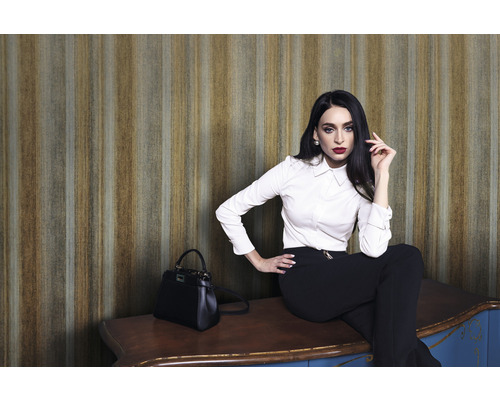 Kvinna sitter på ett skåp framför en randig tapet