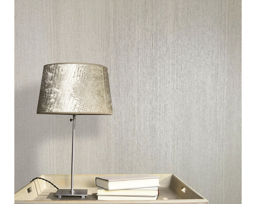 Scen med en strukturerad tapet, en lampa och böcker på ett bord