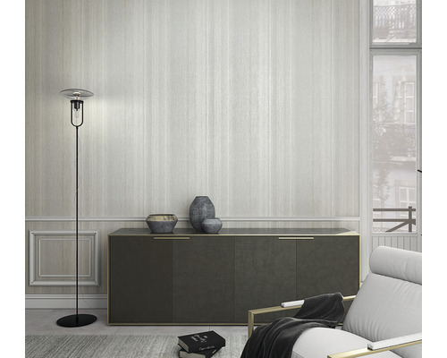 Vardagsrum med golvlampa, byrå och fåtölj framför en randig tapet