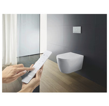 Badrumsscen med vägghängd duschtoalett och fjärrkontroll för styrning