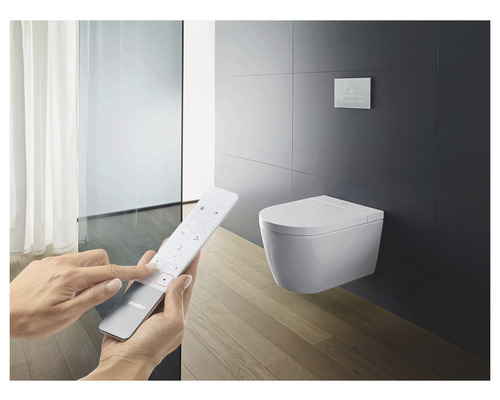 Badrumsscen med vägghängd duschtoalett och fjärrkontroll för styrning