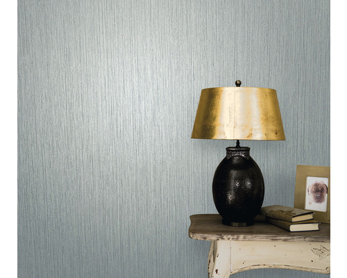 Närbild av en vägg med strukturtapet bredvid ett bord med lampa