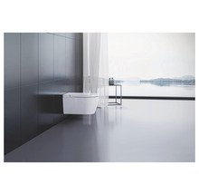 Modernt badrum med vägghängd toalett och utsikt över en sjö