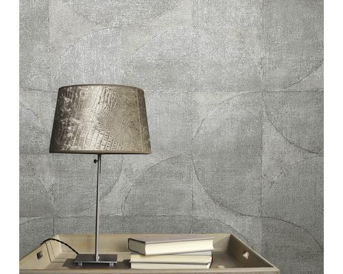 Närbild av en strukturerad tapet med cirkelmönster, kompletterad med en bordslampa och böcker på en bricka