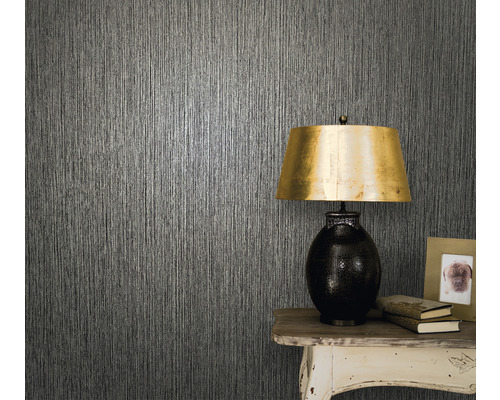 Närbild av en vägg med strukturtapet, ett bord och en bordslampa.