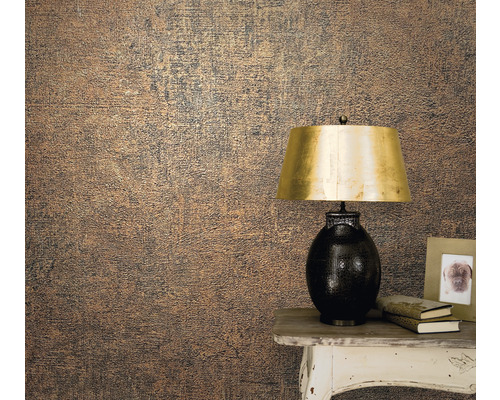 Närbild av en vägg med en strukturtapet bredvid ett bord med en lampa, böcker och en fotoram.