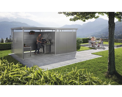 Övertäckt grillplats med man som grillar och familj i bakgrunden