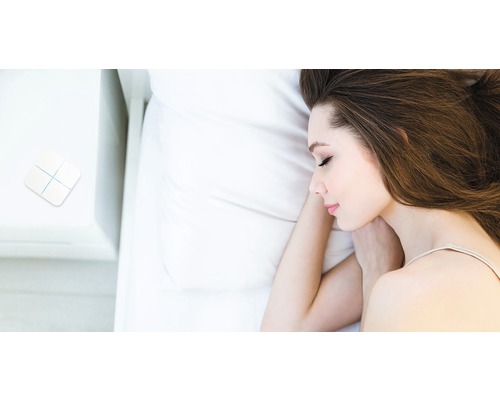 Kvinna sover i sängen med Smart Home-omkopplare på nattduksbordet