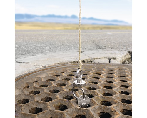 Nyckel på en magnet, fäst på ett rep ovanför ett brunnslock