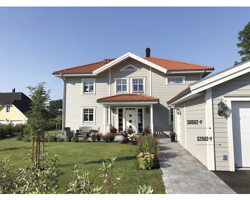 Exteriör av ett tvåvåningshus med garage och välskött trädgård