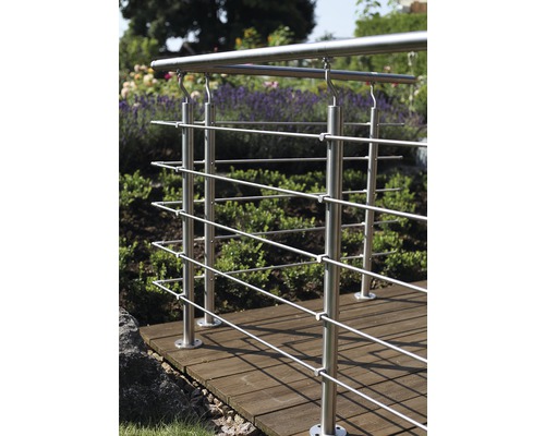 Rostfritt stålräcke på en träterrass i en trädgård.