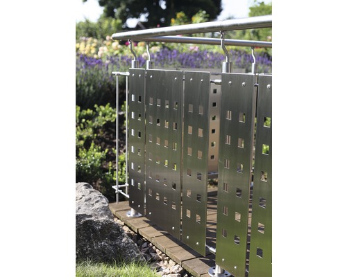 Rostfritt stålräcke med fyrkantiga utskärningar i en trädgård