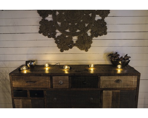 Byrå med lådor, dekoration och ljusslinga framför en trävägg