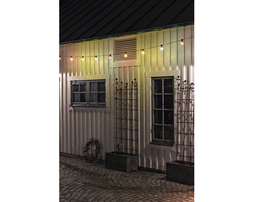 Exteriör av ett hus med fönster, blomlådor och en ljusslinga.