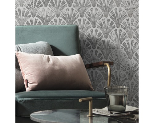 Scen med fåtölj, kuddar och mönstrad tapet i Art Deco-stil