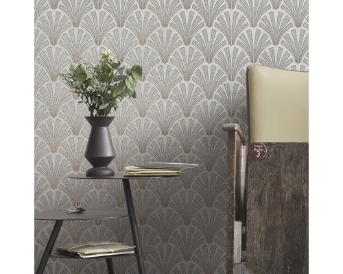 Närbild av en vägg med en tapet med ett fläktformat mönster i ett rum med ett bord och en stol