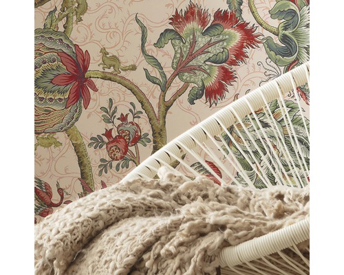 Detalj av ett rum med en mönstrad tapet, en fåtölj och en filt.