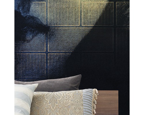 Närbild av en vägg med mörkblå mönstrad non-woven tapet och gyllene accenter ovanför en säng