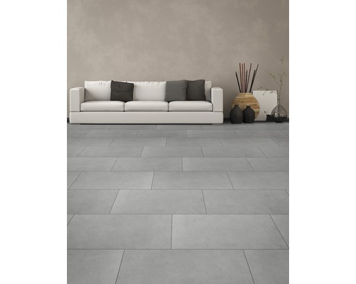 Ljust vardagsrum med golvplattor, soffa och dekorationer.