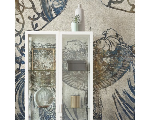 Dekorativt vardagsrum med ett vitt glasskåp mot en mönstrad tapet.