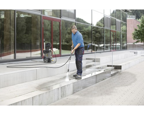 En man rengör en betongtrappa med en högtryckstvätt.