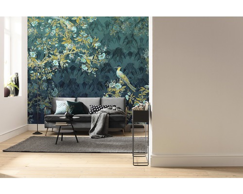 Vardagsrum med soffa framför en mönstrad tapet med växt- och fågelmotiv