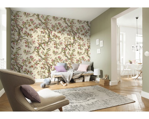 Vardagsrum med blommig tapet med fågelmotiv, fåtölj och matta för en ljus och organiserad atmosfär.